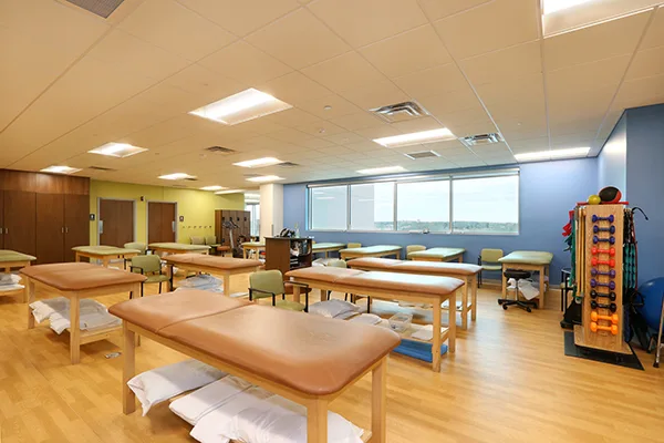 A University Orthopedics therapy gym with treatment tables and weight racks
