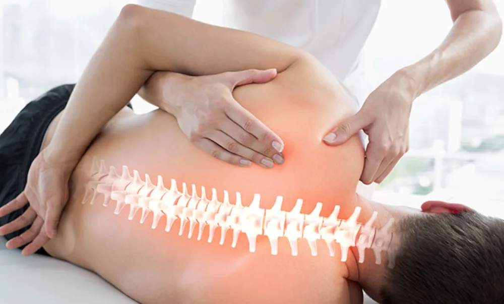 A physical therapist working on a patient's shoulder and upper back, with the spine highlighted